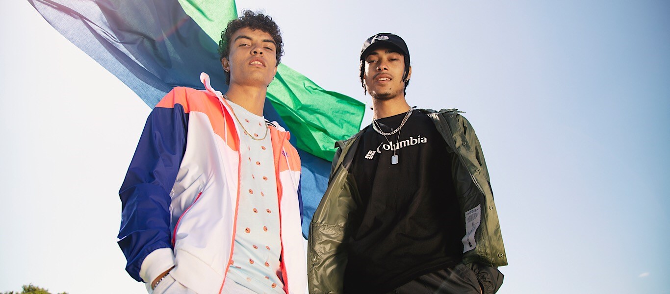 Zwei junge Männer vor bunten Fahnen